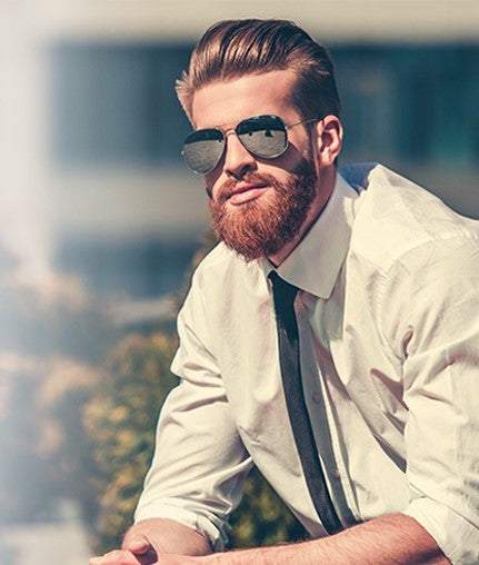 Stylish man with well-groomed beard wearing sunglasses and white shirt demonstrating beard care tips for cold weather protection