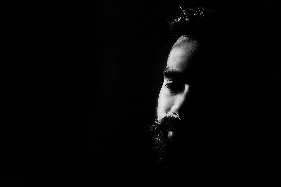 close-up artistic black and white portrait of a bearded man with shadows highlighting facial hair details